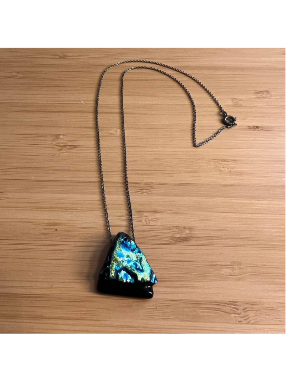 Silver necklace with iridescent blue and green colors on black gemstone/rock